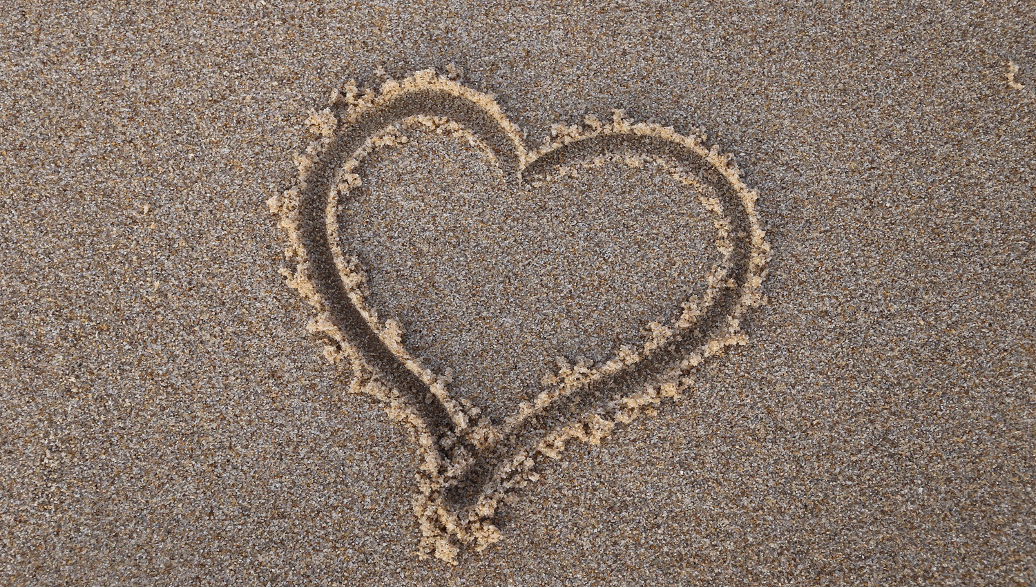 אהבה - תמונה של לב מצויר בחול על שפת הים